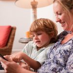 Son using a digital tablet with his mother (Getty Images)