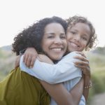 Mother and son hugging outdoors (Getty Images)